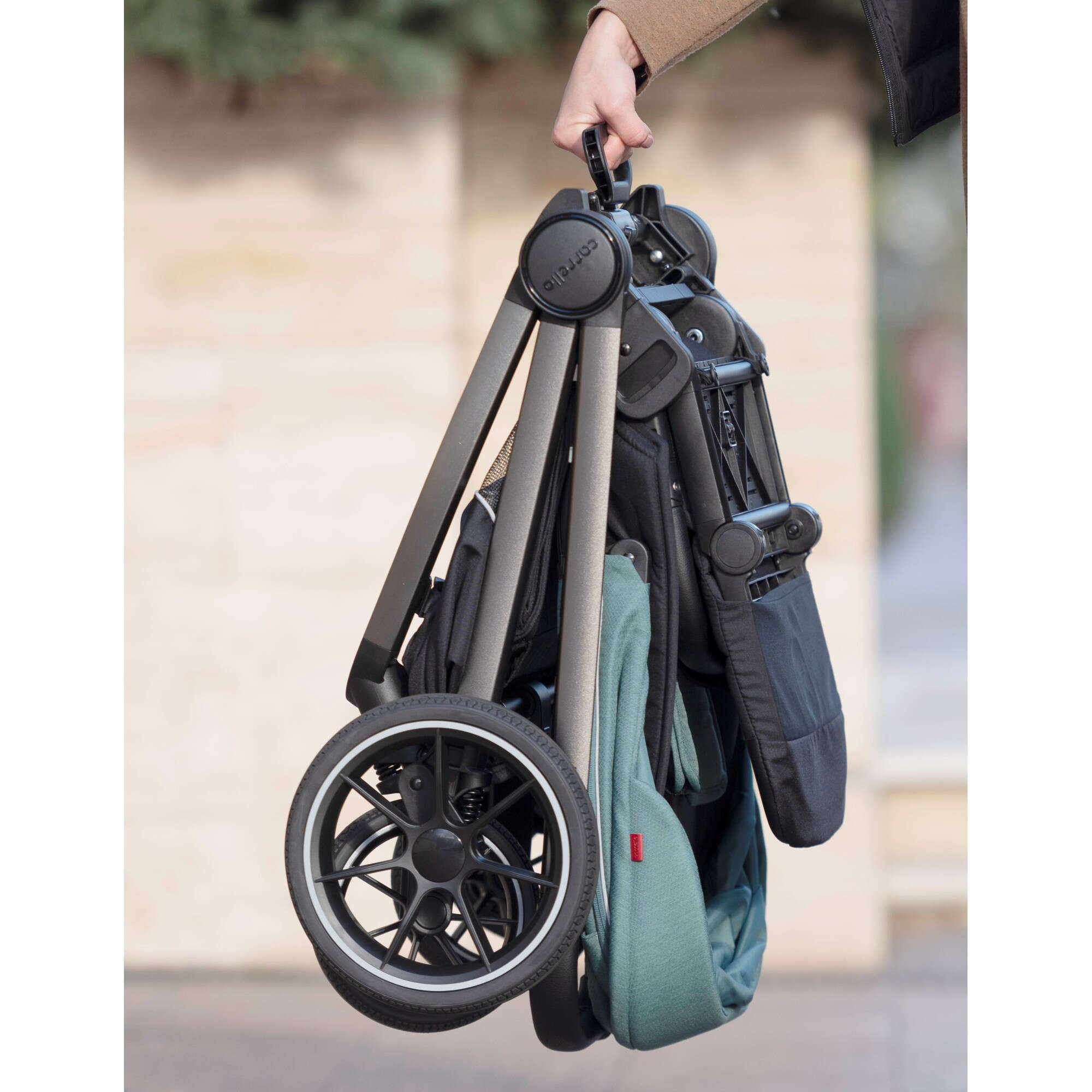 Складена коляска Carrello Ultra блакитного кольору в руці для перенесення 